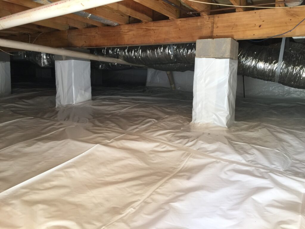 Same crawl space after encapsulation: clean white vapor barrier across floor and piers